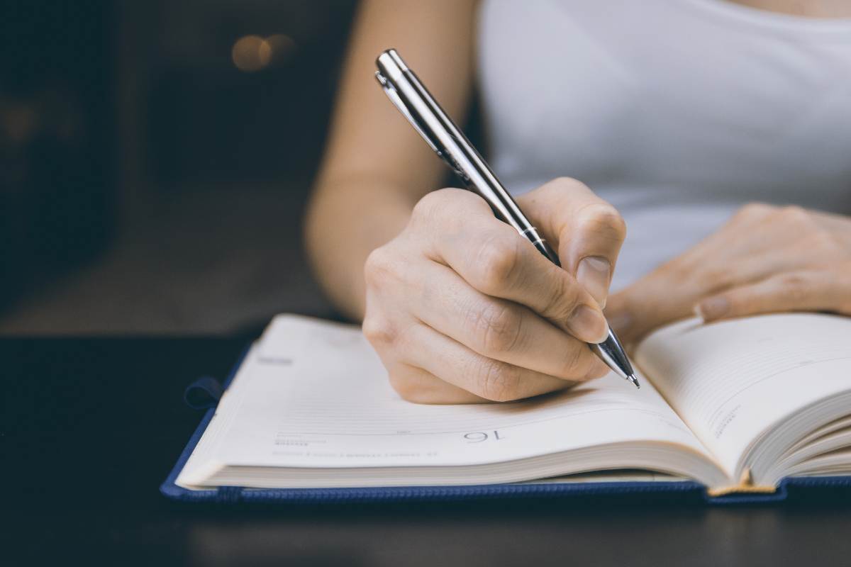 persona escribiendo con pluma en libreta