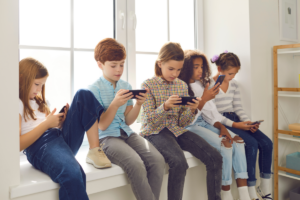 Varios niños miran un móvil distraídos.