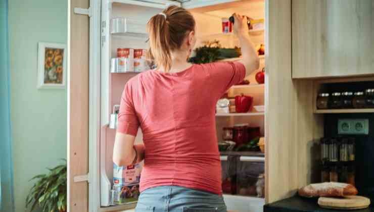 donna che prende cibo dal frigorifero 
