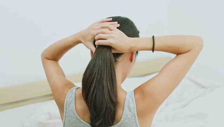 donna che si fa la coda ai capelli