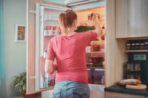 donna che mette cibi in frigorifero