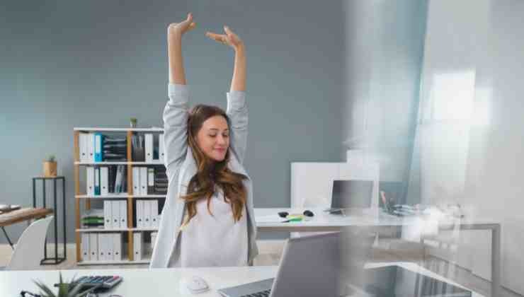 ragazza che si stira le braccia davanti la scrivania