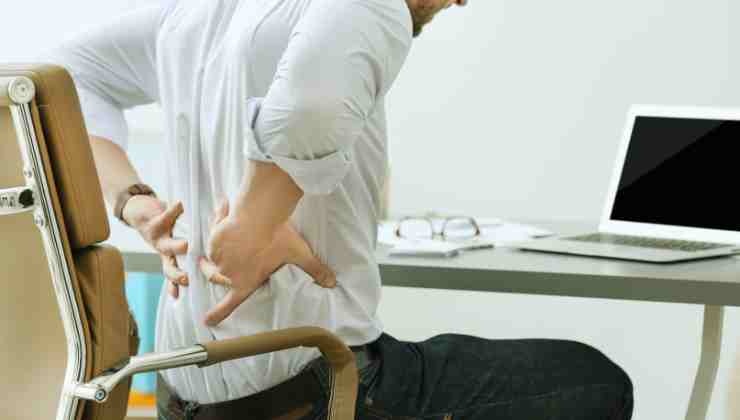 uomo seduto alla sedia con dolore di schiena