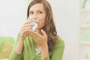 donna beve un bicchiere d'acqua