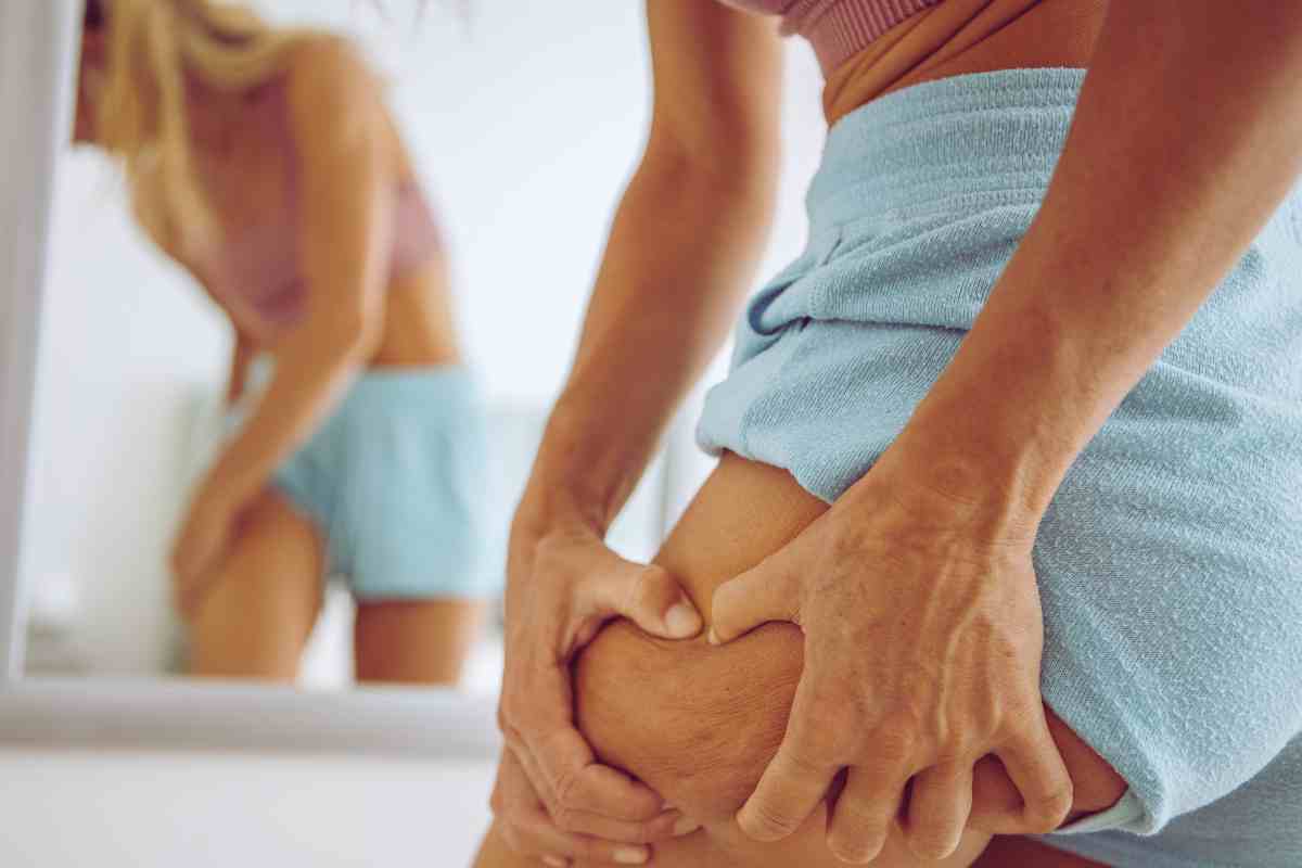 mujer que se mira la celulitis en el espejo