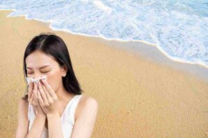 ragazza che si soffia il naso e spiaggia