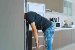 uomo che si infila nel freezer con la testa