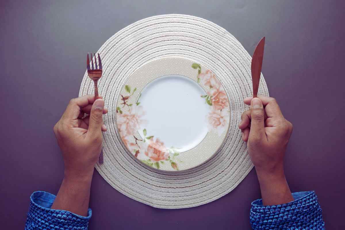 Plato vacío y manos con cubiertos