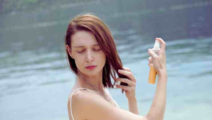 mujer poniéndose spray en el cabello