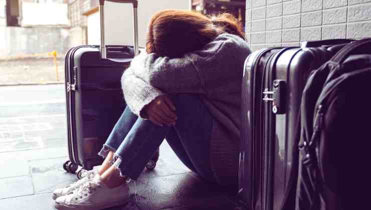ragazza accovacciata vicino alle valigie