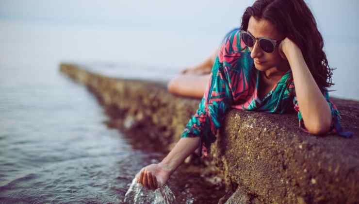 donna sdraiata tocca l'acqua del mare