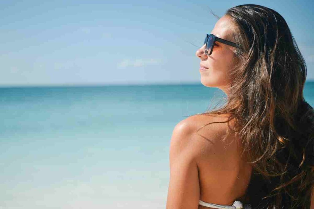 donna di spalle con costume e occhiali da sole