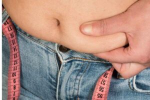 Uomo con metabolismo lento che si tocca la pancetta in eccesso