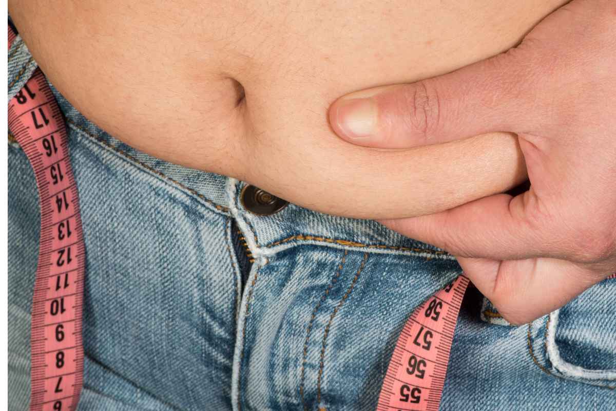 Uomo con metabolismo lento che si tocca la pancetta in eccesso