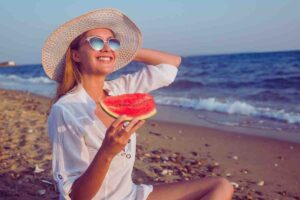 donna che mangia cocomero in spiaggia