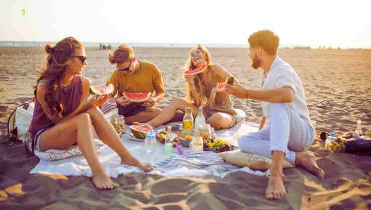 amici mangiano cocomero in spiaggia
