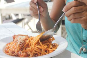 Ragazza che mangia un bel piatto di spaghetti con il pomodoro