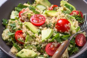 Piatto fondo con all'interno una Insalata di quinoa con pomodori e avocado