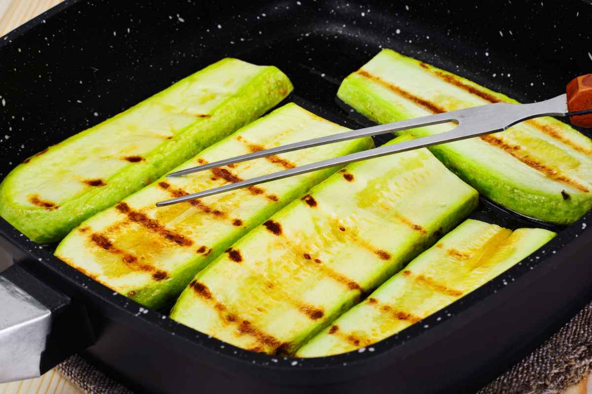 Zucchine che stanno grigliando su una piastra di ghisa