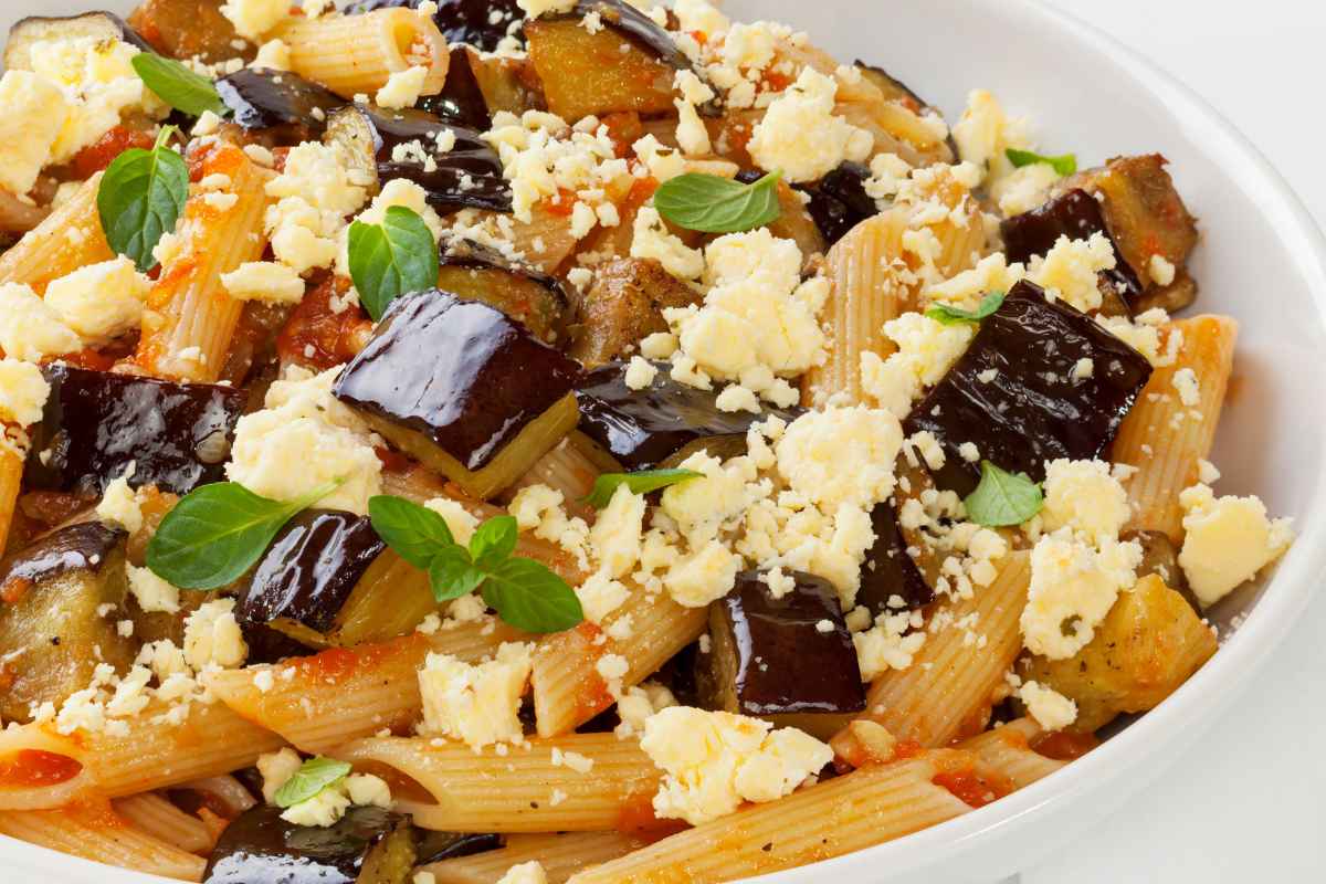 Primo piano di un piatto di pasta alla Norma fatto con le melanzane arrosto invece che fritte e ricotta salata