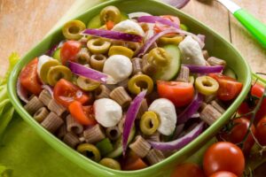 Ciotola verde con all'interno un'insalata di pasta di ceci con verdure