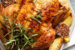 Primo piano di un pollo intero cotto al forno con rosmarino e aglio