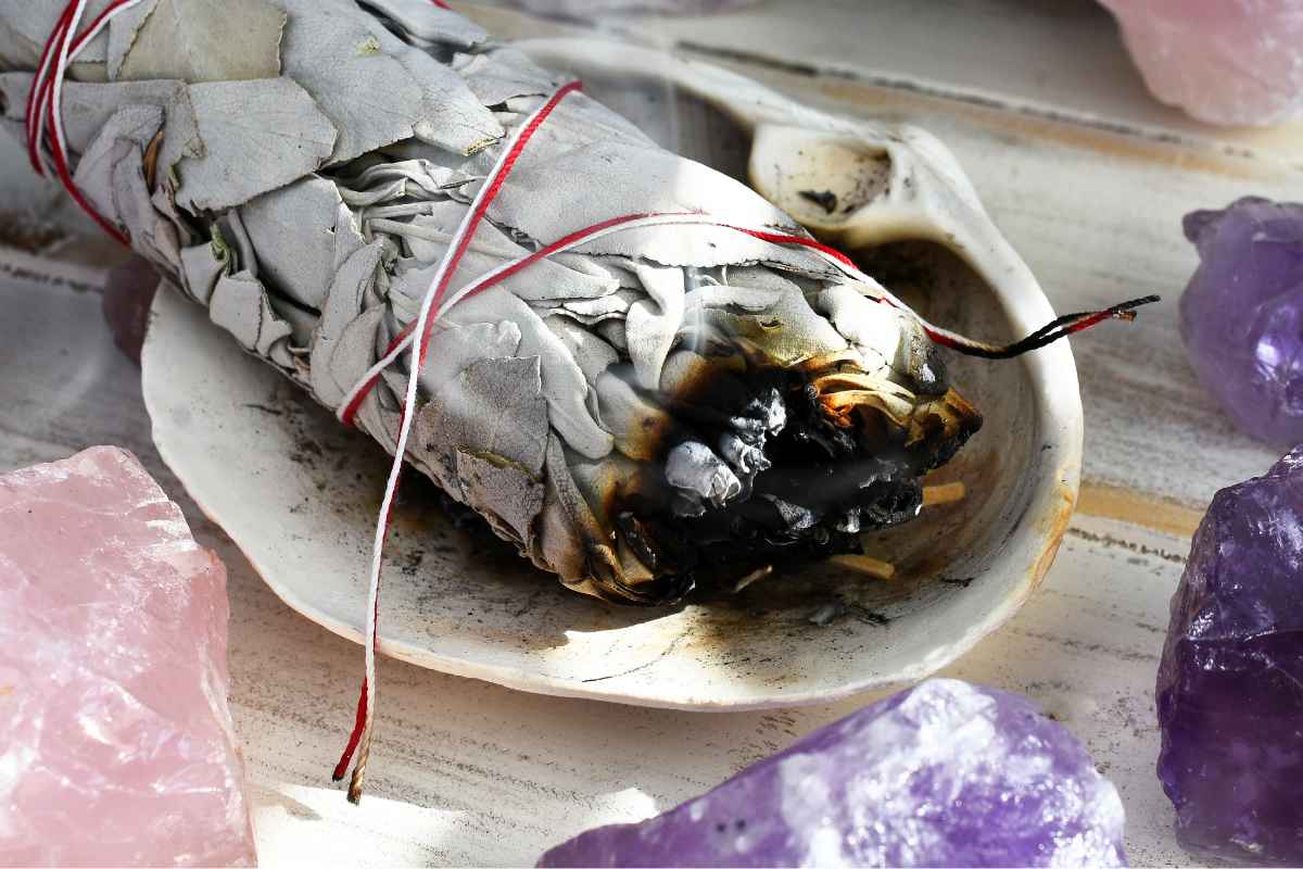 Smudge di salvia bianca da bruciare circondato da pietre di ametista e quarzo rosa