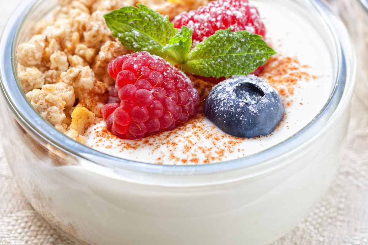 Yogurt greco con mirtilli, lamponi e granola per colazione