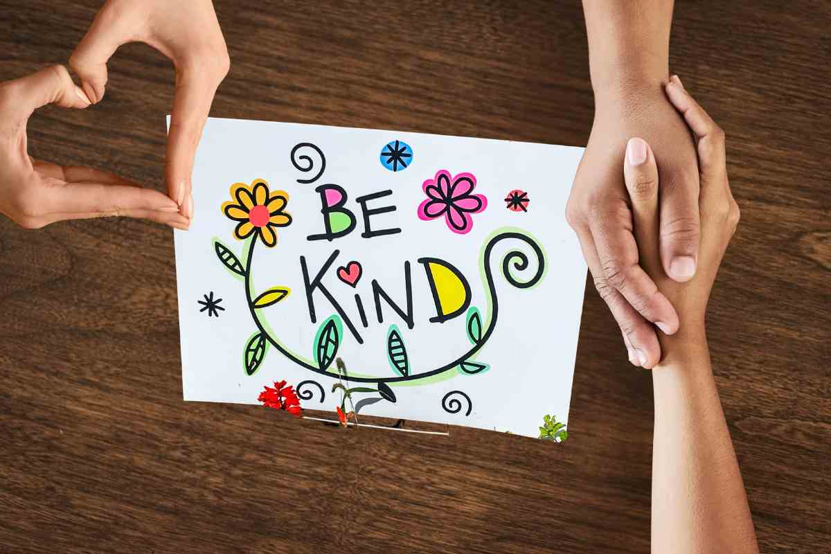 mani che si stringono e cartello be kind