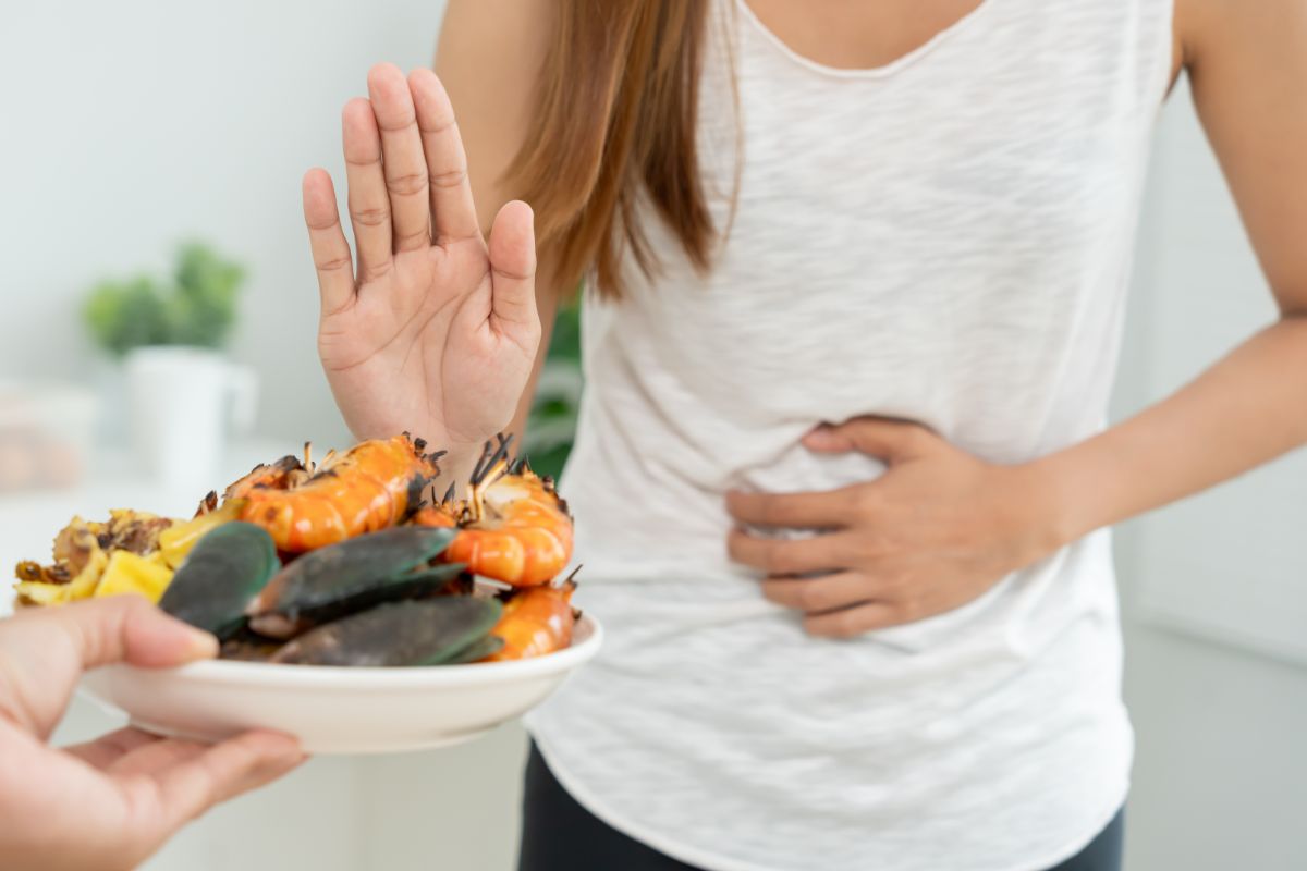 Mujer con alergia alimentaria apartando un plato